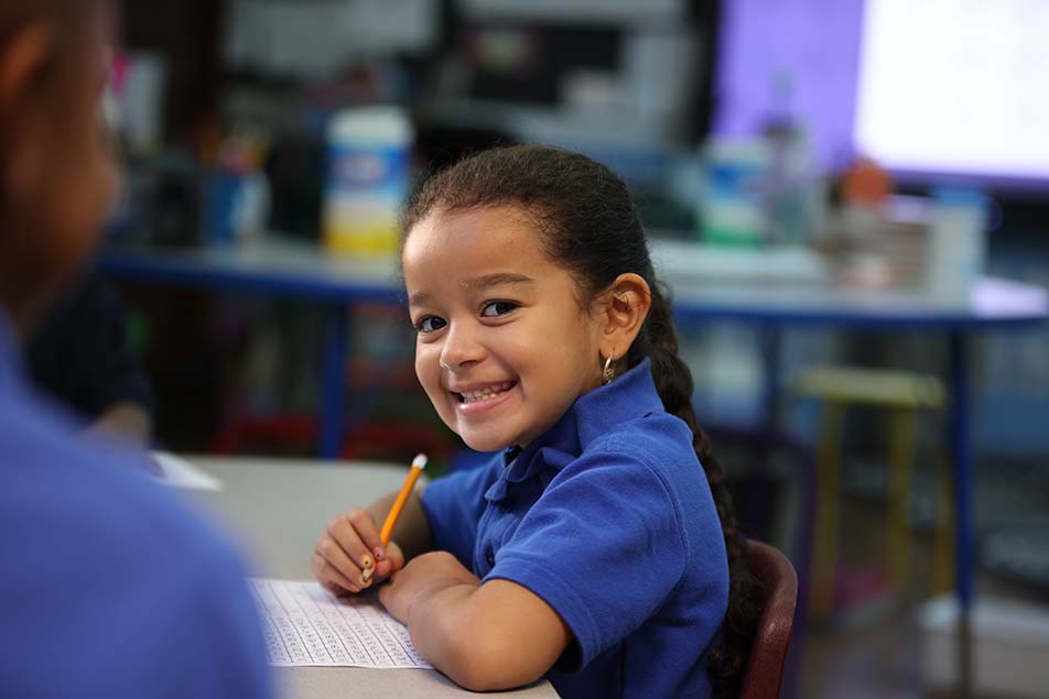 student in classroom smiling at camera